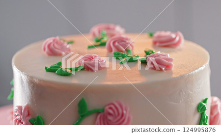 Elegant cake on turntable.Pink buttercream flowers on frosting. Bakery, pastry 124995876