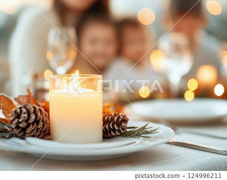 warm family gathering around beautifully set table with glowing candle, pinecones, and autumn leaves, creating cozy atmosphere 124996211