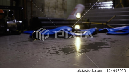 Water pooling on floor with equipment scattered in dimly lit area Water pooling on floor with equipment scattered in dimly lit area 124997023