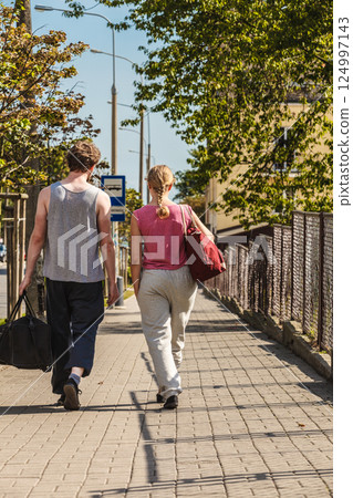 Couple man and woman walking with sport bags. 124997143