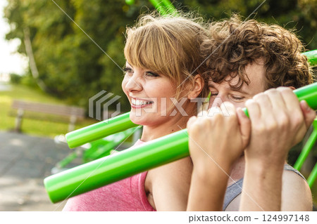 Man and woman exercising on pulldown outdoor. 124997148