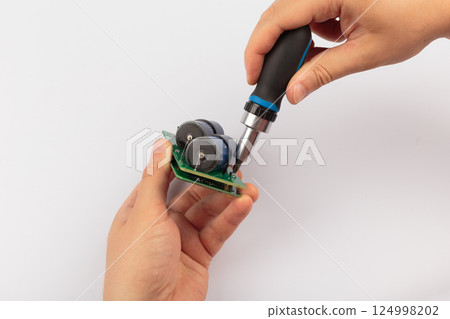 Hands of a master holding an electronic board on a 124998202