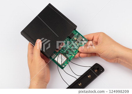 Hands of a master holding an electronic board on a 124998209