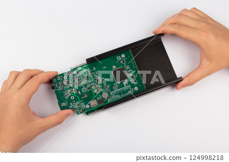 Hands of a master holding an electronic board on a 124998218