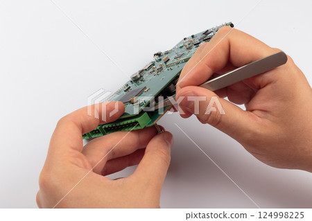 Hands of a master holding an electronic board on a 124998225