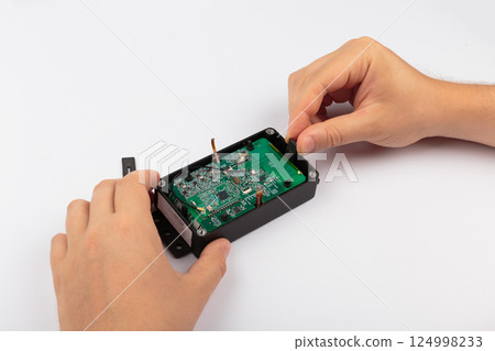 Hands of a master holding an electronic board on a 124998233
