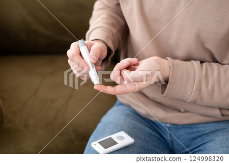 Man checking blood sugar level with a glucometer at home. Diabetes management, healthcare, medical monitoring concept 124998320