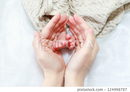 Newborn's foot and mama's hand 124998787