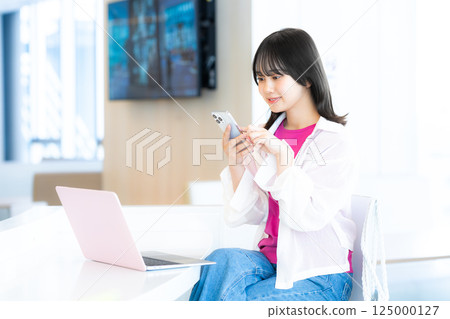 一個微笑的女人看著智能手機 一個微笑的女人看著智能手機 125000127