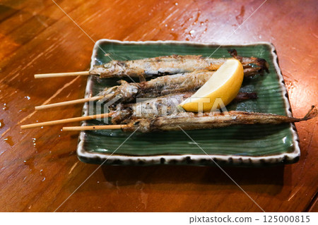 close up of four Japanese skewer grilled capelin dish on a plate 125000815