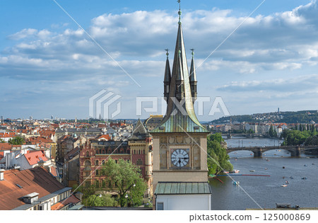 Clock tower rising above Prague's picturesque red roofs with Vltava river and bridges in background 125000869