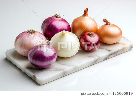 Several colorful onions resting on a marble cutting board 125000919