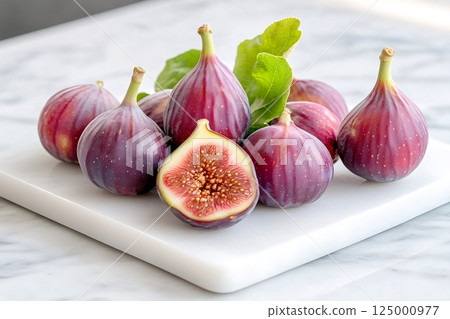 Fresh figs with leaves resting on white marble cutting board 125000977