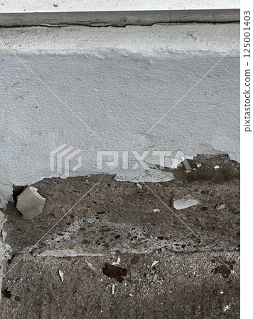 Deteriorated concrete wall with peeling paint 125001403