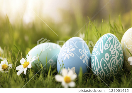 Blue painted Easter eggs with floral ornament on grass among aisies in sunny morning. Easter card. 125001415