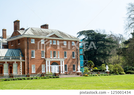 An old red brick building under bright sunlight in Hatchlands Park, a suburb of London 125001434