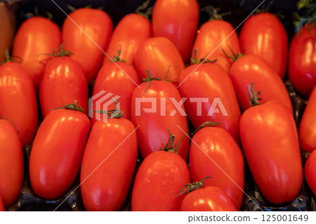 Bright red Roma tomatoes with a smooth glossy texture neatly arranged at a farmers market. Ideal for Bright red Roma tomatoes with a smooth glossy texture neatly arranged at a farmers market. Ideal for 125001649