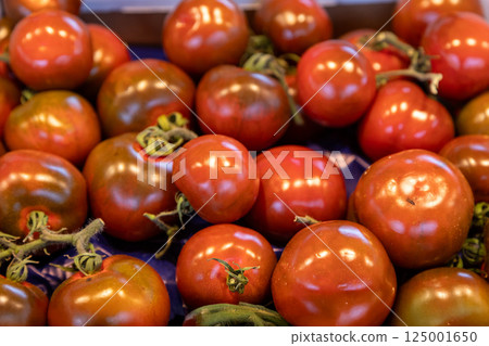 Vibrant heirloom tomatoes with a glossy texture and deep colors displayed at a farmers market. Ideal 125001650