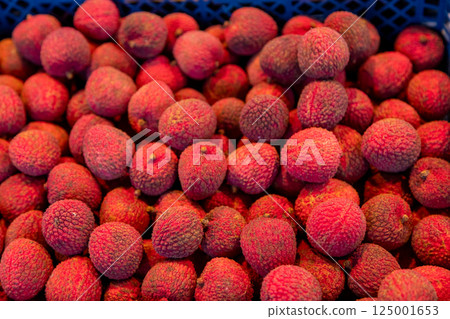 Fresh lychee fruits in a market crate. Exotic tropical fruit with textured skin. Perfect for food Fresh lychee fruits in a market crate. Exotic tropical fruit with textured skin. Perfect for food 125001653
