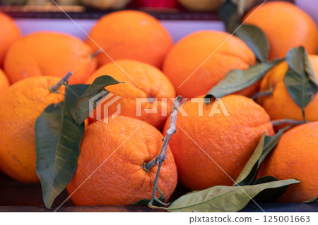 Bright and juicy organic oranges with fresh green leaves in a market setting. Perfect for food Bright and juicy organic oranges with fresh green leaves in a market setting. Perfect for food 125001663