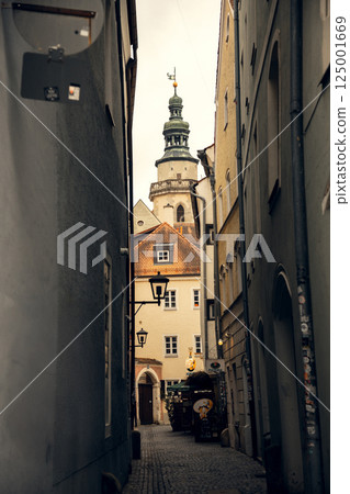 Narrow European alley with historic architecture and a church tower. A charming cobblestone alley in 125001669