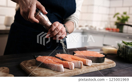 Woman Salting Raw Red Fish Salmon For Cooking 125001969