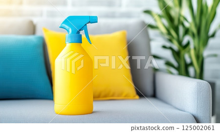Yellow spray bottle on gray couch with colorful pillows in living room. 125002061
