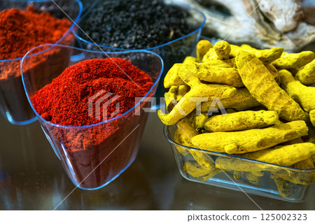 Indian spices. Ground red hot chili pepper and dry yellow turmeric roots in glass bowl. 125002323
