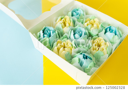A box of colorful, flower-shaped desserts on a dual-tone background. A box of colorful, flower-shaped desserts on a dual-tone background. 125002328