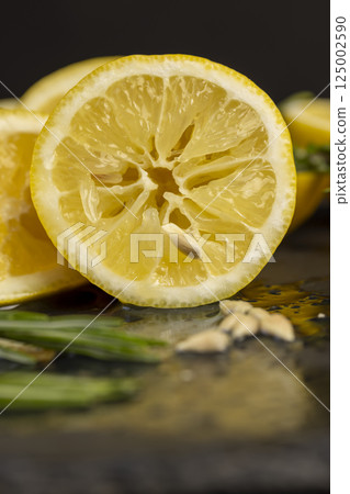 one lemon on a black slate , freshly sliced lemon on a black board close up, side view 125002590