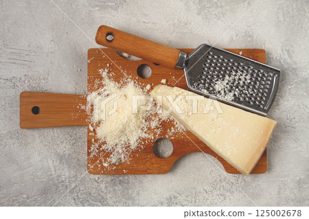 Freshly sliced and grated cheese, parmesan cheese, on a wooden chopping board, rustic style, no people Freshly sliced and grated cheese, parmesan cheese, on a wooden chopping board, rustic style, no people 125002678