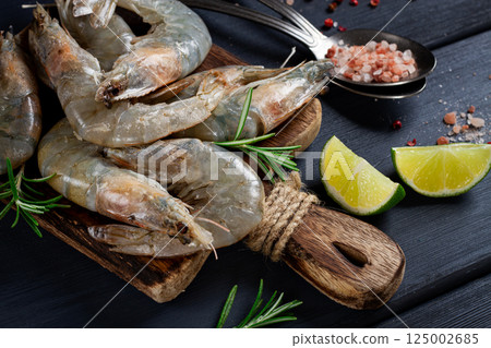 Fresh raw, white-footed shrimp, tiger prawns vannamei, on a wooden cutting board, with lime slices, and seasonings, Fresh raw, white-footed shrimp, tiger prawns vannamei, on a wooden cutting board, with lime slices, and seasonings, 125002685