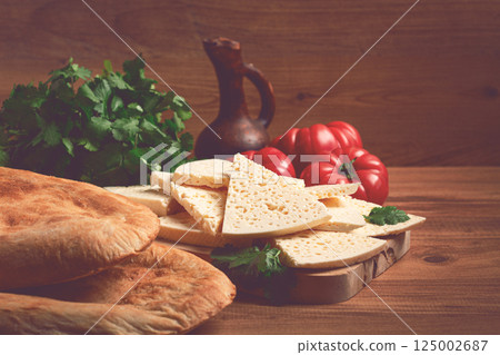 Georgian sliced cheese,on a wooden chopping board, with tomatoes with herbs and lavash, rustic style, Georgian cuisine, no people Georgian sliced cheese,on a wooden chopping board, with tomatoes with herbs and lavash, rustic style, Georgian cuisine, no people 125002687