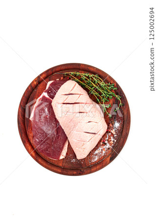 Fresh raw duck breasts, on a wooden chopping board, with herbs and spices, on a white background, no people 125002694