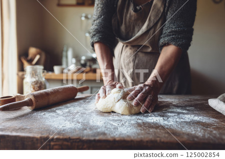 Hands kneading bread dough in cozy kitchen 125002854