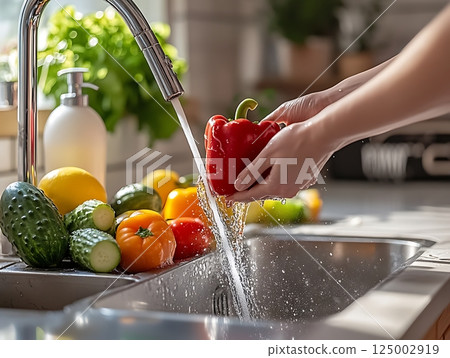 Cleaning Fresh Bell Peppers and Vegetables Under Running Water in Bright Kitchen Setting 125002919