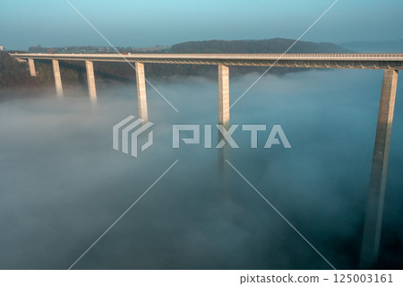 Autobahn bridge over dense fog, drone aerial view, at sunrise in Germany 125003161