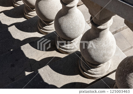 Stone balusters line a staircase, casting intricate geometric shadows 125003463