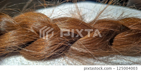 Close-up of braided hair. Women's blonde hair braided into a braid. Close-up of braided hair. Women's blonde hair braided into a braid. 125004003