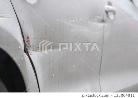 Vehicle with noticeable scratches and dents parked on city street Vehicle with noticeable scratches and dents parked on city street 125004011