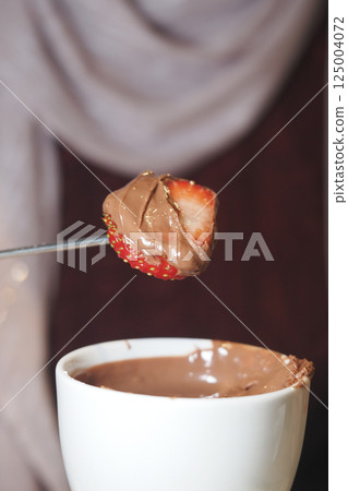 Enjoying chocolate-covered strawberries at a dessert party Enjoying chocolate-covered strawberries at a dessert party 125004072