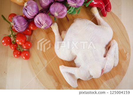 Fresh chicken and vegetables prepared on wooden cutting board Fresh chicken and vegetables prepared on wooden cutting board 125004159
