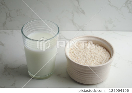 Glass of milk and bowl of rice on a marble countertop 125004196