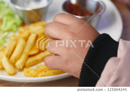 Child enjoying fries and dipping sauces at casual dining restaurant Child enjoying fries and dipping sauces at casual dining restaurant 125004245
