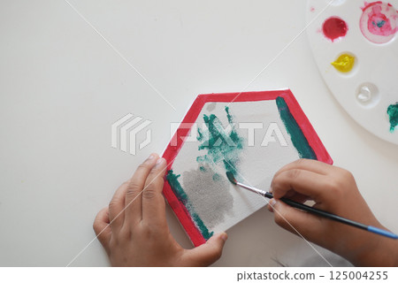 Child painting a colorful hexagonal canvas in an artistic activity 125004255