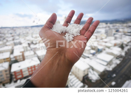 Snowy hand holds fresh snow over a winter city landscape 125004261