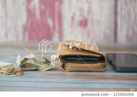 Wallet with cash and coins on wooden table near smartphone Wallet with cash and coins on wooden table near smartphone 125004268