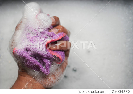 Cleaning with a soapy sponge in a sink full of bubbles Cleaning with a soapy sponge in a sink full of bubbles 125004270