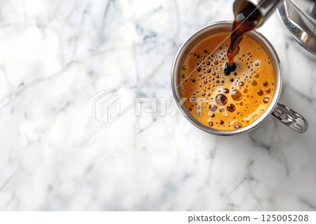 Overhead view of fresh black coffee being poured into white mug on marble tabletop 125005208