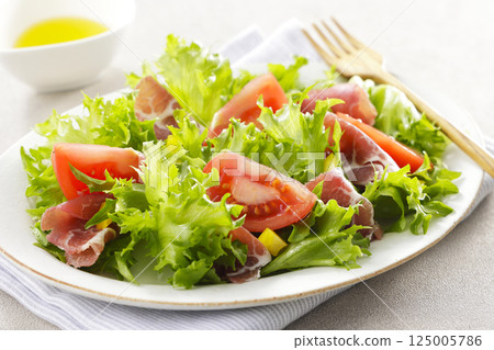 Tomato, prosciutto and leaf lettuce salad 125005786